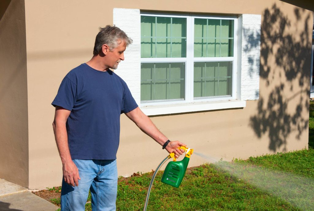 person using weed and feed to improve their lawn appearance